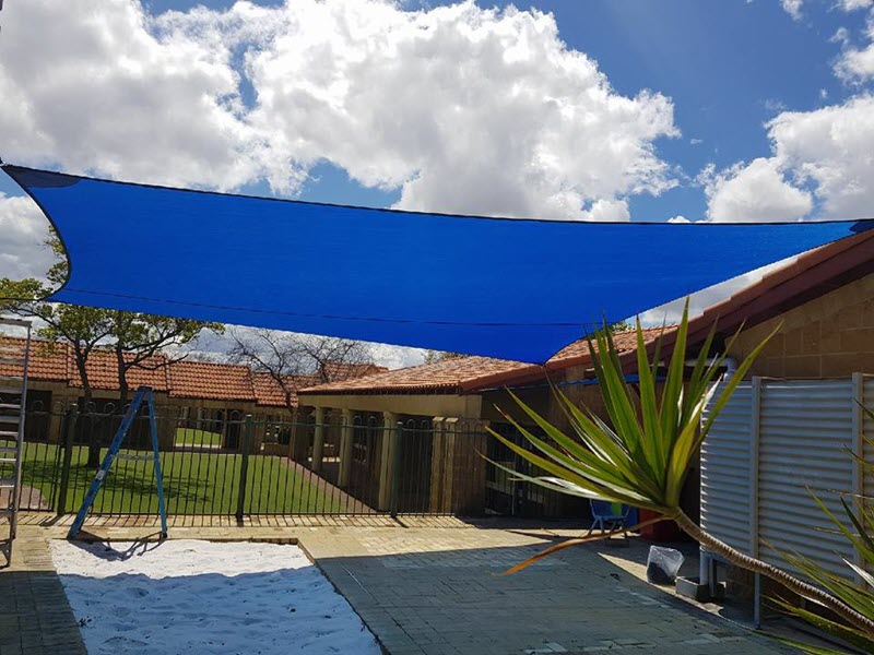 Blue shade sail over daycare centre playground.